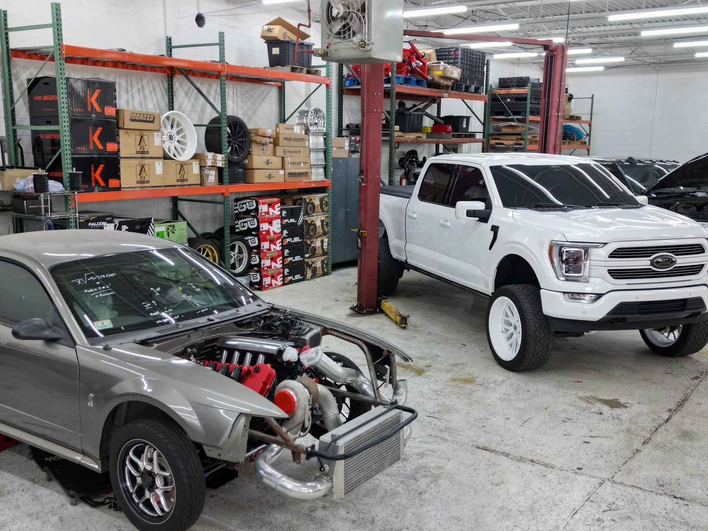 The Street Justice Performance shop floor: parts shelving, a turbocharged project car, and a lifted Ford F-150